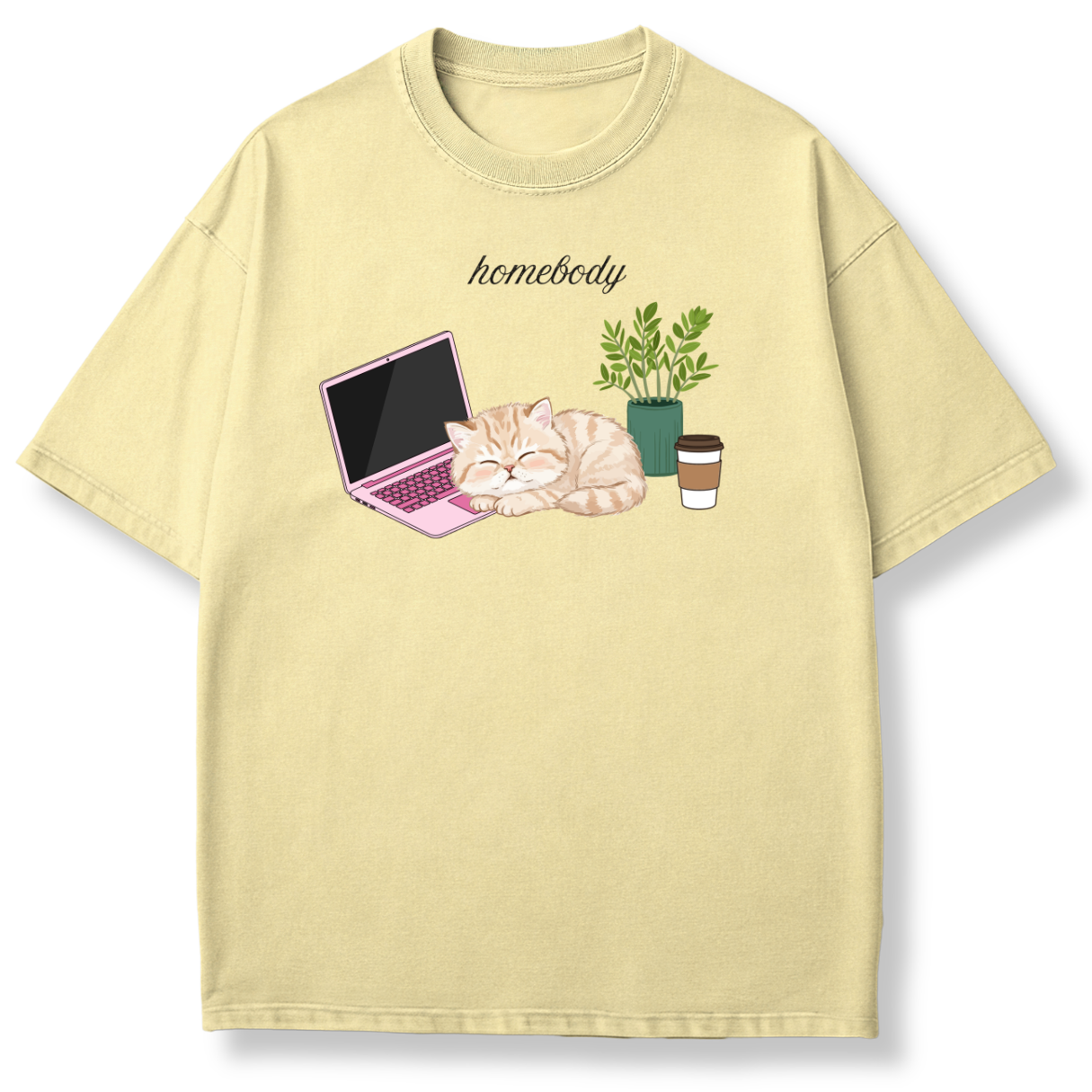 A pale yellow short-sleeve t-shirt with a graphic of a sleeping orange tabby cat next to a pink laptop, a green potted plant, and a coffee cup, with the word 'homebody' printed above.