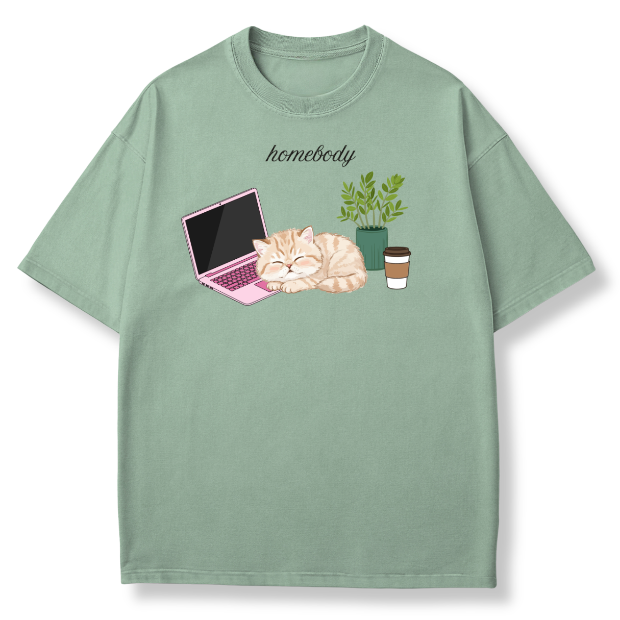 A sage green short-sleeve t-shirt with a cute graphic of a sleeping orange tabby cat next to a pink laptop, a green potted plant, and a coffee cup, with the word 'homebody' printed above.