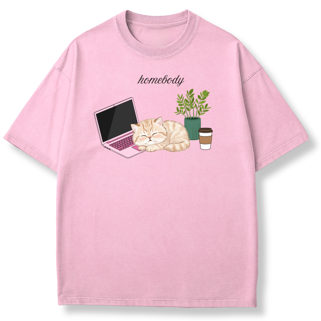 A light pink short-sleeve crewneck t-shirt featuring a cute graphic of a sleeping orange tabby cat on a laptop next to a potted plant and a coffee cup, with the word 'homebody' printed above.